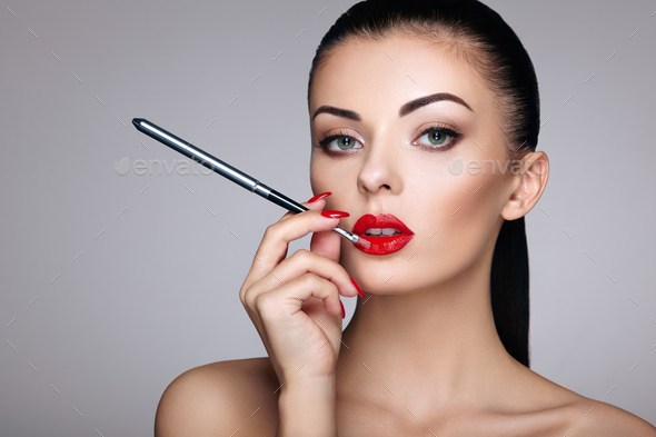 Beautiful woman paints lips with lipstick - Stock Photo - Images