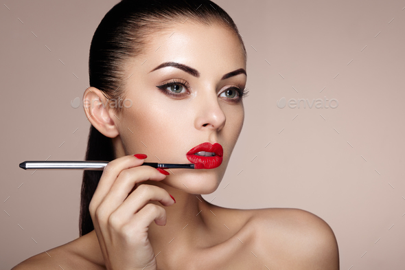 Beautiful woman paints lips with lipstick - Stock Photo - Images