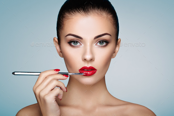 Beautiful woman paints lips with lipstick - Stock Photo - Images