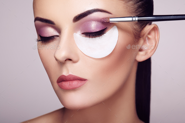 Makeup artist applies eye shadow - Stock Photo - Images