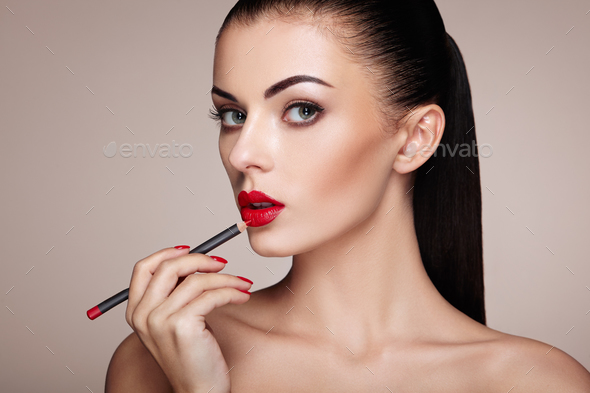 Beautiful woman paints lips with lipstick - Stock Photo - Images