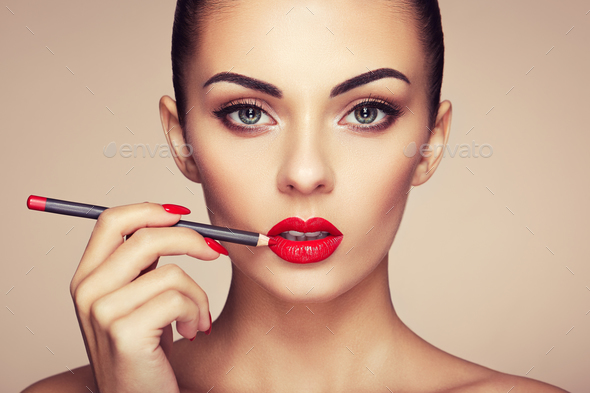 Beautiful woman paints lips with lipstick - Stock Photo - Images