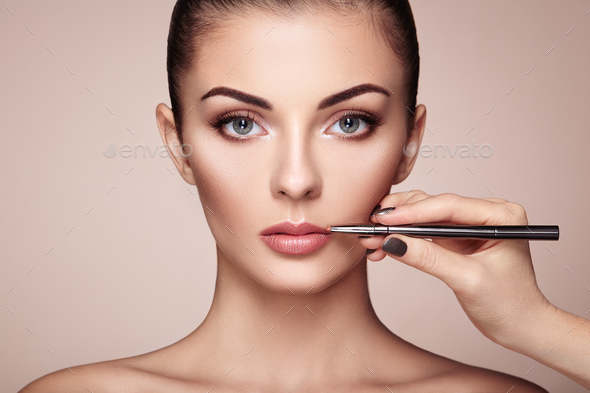 Beautiful woman paints lips with lipstick - Stock Photo - Images