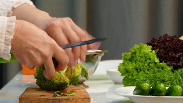 Chef Cutting Fresh Broccoli On Carving Board