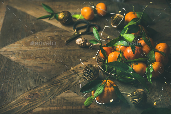 Fresh tangerines, decoration toys and light garland over rustic background - Stock Photo - Images
