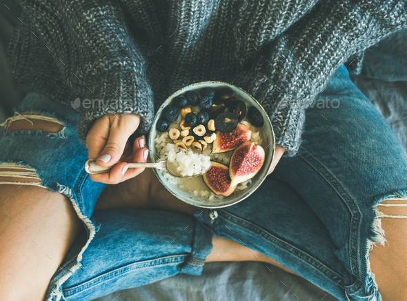 Woman in shabby jeans and sweater eating healthy breakfast - Stock Photo - Images