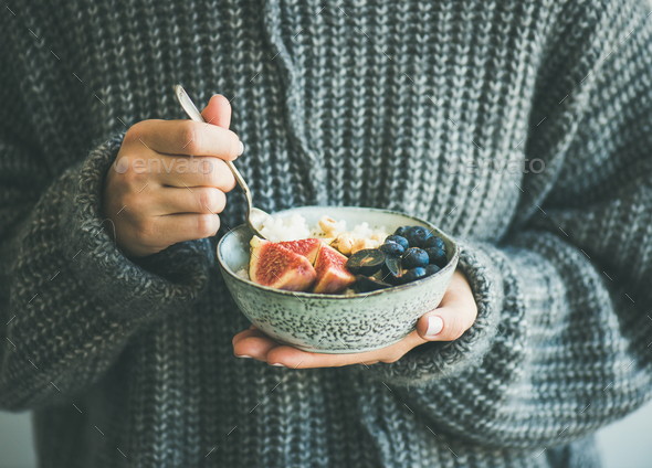 Woman in grey woolen sweater eating rice coconut porridge - Stock Photo - Images