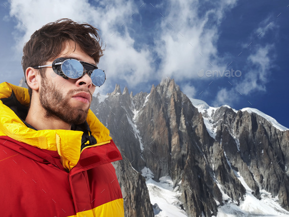 Mountaineer in winter clothes with hiking equipment against snowy landscape