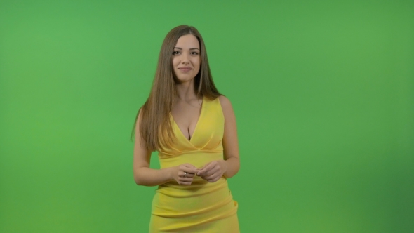 Beautiful Young Girl in a Yellow Dress, on a Green Screen. She Turns and Makes a Gesture with Her