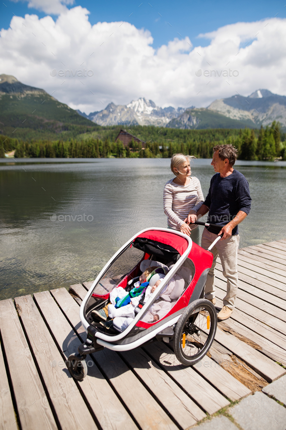 Senior couple with grandchildren in jogging stroller.
