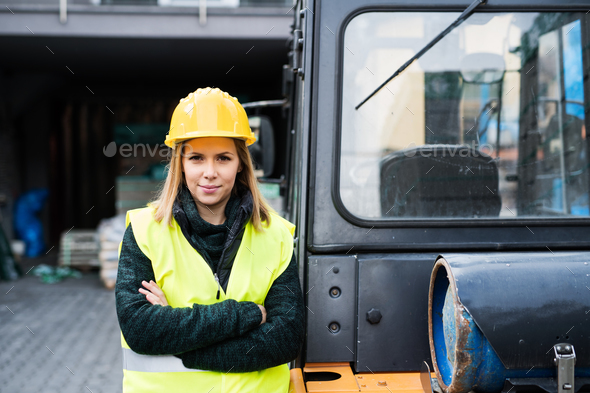 Woman forklift truck driver in an industrial area. Stock Photo by halfpoint