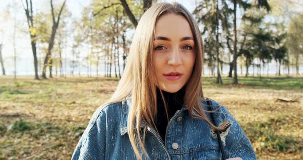 Portrait of Young Attractive Female Looking at the Sliding Camera on Autumn Park. Cheerfully Pretty alt