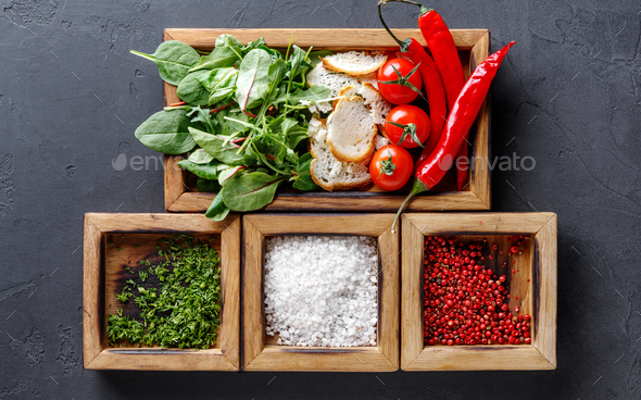 Woman holding cooking ingredients and herbs in wooden box on dark background - Stock Photo - Images