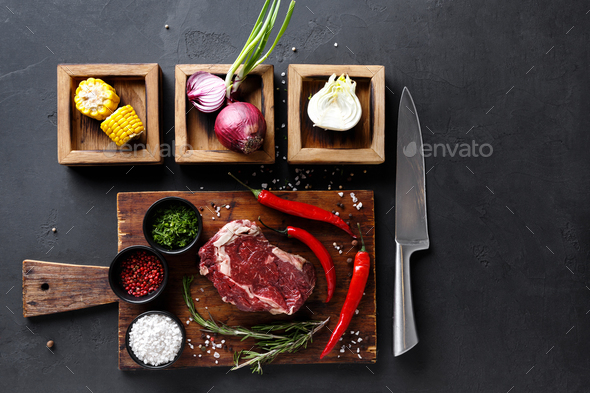 Rib eye steak with spices on wooden desk and diverse cooking ingredients in wooden boxes. - Stock Photo - Images