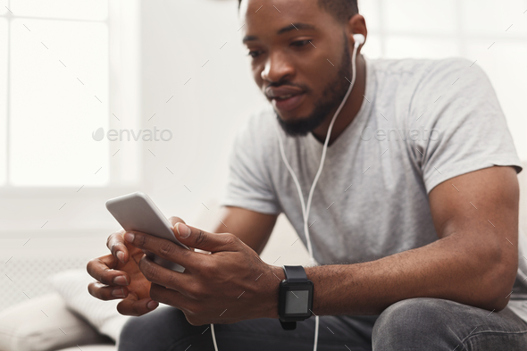 Young african-american man in earphones with mobile - Stock Photo - Images