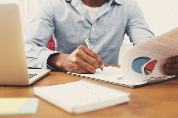 Black man reading documents in modern office - Stock Photo - Images