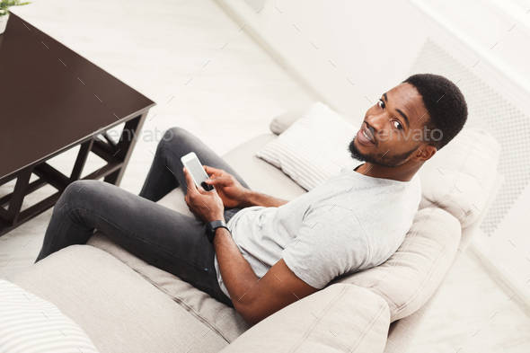 Happy young man at home messaging on mobile - Stock Photo - Images