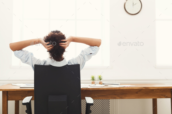 Business woman resting in office with hands behind her head - Stock Photo - Images