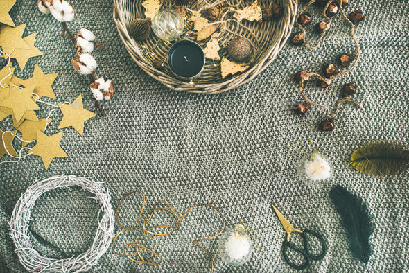 Flat-lay of Christmas toys, garlands, lights, wreath over grey blanket