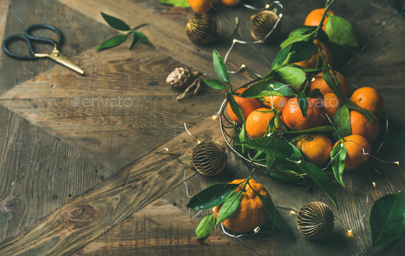Fresh tangerines, decoration toys and light garland over rustic background - Stock Photo - Images