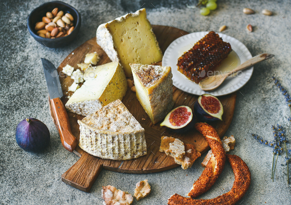Cheese assortment, figs, honey, freshly baked bread and nuts - Stock Photo - Images