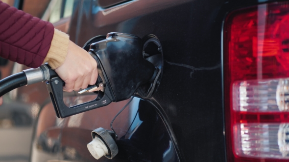 Hand with a Gun To Refuel the Car. A Woman Fills Her Car alt