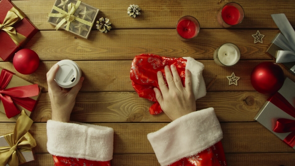 Santa Claus Drinks Coffee By Christmas Wooden Table, Top Down Shot