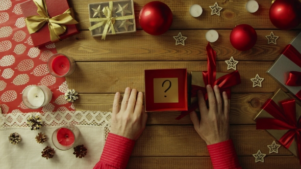 Man Opens Christmas Gift Box with Sticky Note with Question Mark on It, Top Down Shot