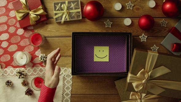 Top Down Shot of Man Opening Christmas Gift Box with Sticky Note with Smile Inside