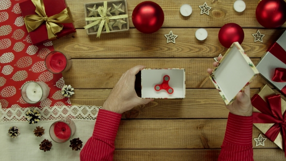 Man Opening Christmas Gift Box with Fidget Spinner Inside, Top Down Shot