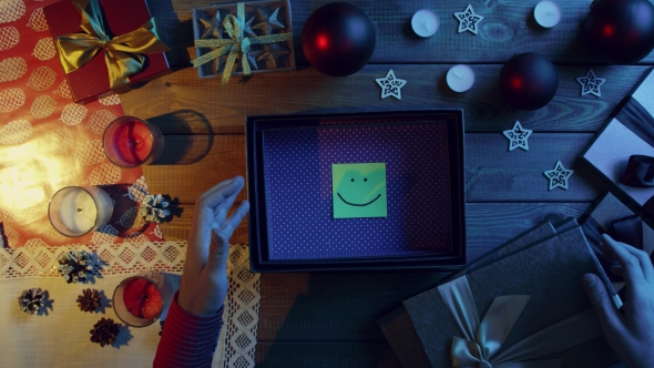 Top Down Shot of Man Opening New Year Present Box with Sticky Note with Smile Inside