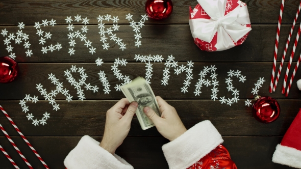 Santa Claus Counts Cash Money By Xmas Decorated Table, Top Down Shot