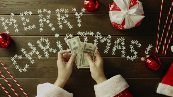 Santa Claus Counts Cash Money By Christmas Decorated Table, Top Down Shot