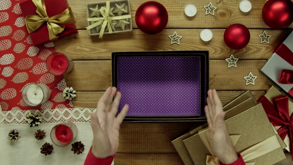 Man Opens Empty Christmas Present Box By Wooden Holiday Table, Top Down Shot