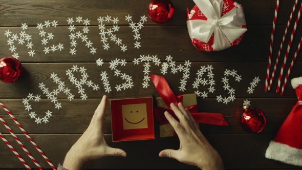 Top Down Shot of Adult Man Opening Christmas Gift Box with Sticky Note with Smile Inside