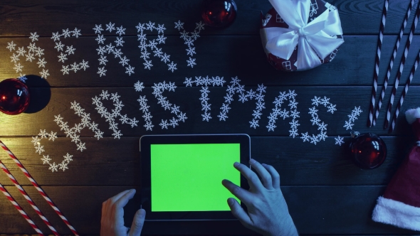 Adult Man Uses Tablet Pc with Green Screen By Xmas Decorated Table, Top Down Shot