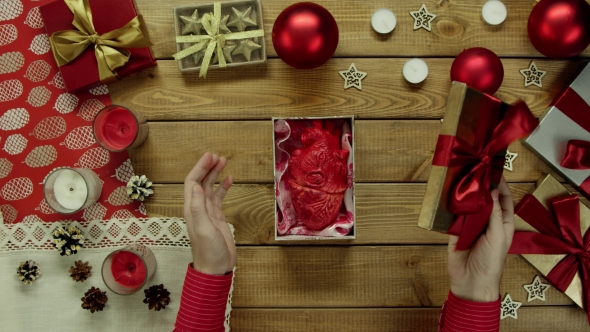 Man Opens Christmas Present with Real Human Heart Made of Plastic Inside on Decorated Wooden Table