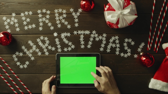 Adult Man Uses Tablet Pc with Green Screen By New Year Decorated Table, Top Down Shot