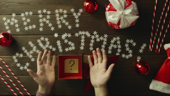 Adult Man Opens Christmas Gift Box with Sticky Note with Question Mark on It, Top Down Shot