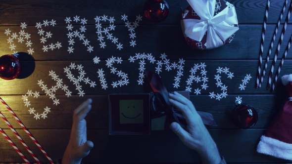 Top Down Shot of Adult Man Opening New Year Gift Box with Sticky Note with Smile Inside