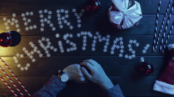 Adult Man with Watch on His Hand Sitting By Decorated Wooden Xmas Table, Top Down Shot