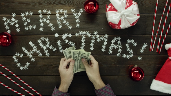 Adult Man Counts Dollars By Xmas Decorated Table, Top Down Shot