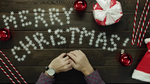 Adult Man with Luxury Watch on His Hand Sitting By Decorated Wooden Christmas Table, Top Down Shot