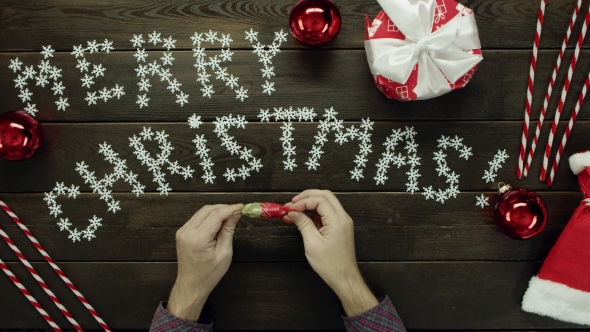 Man Unwraps Candy, Eats It and Throws Wrapper on Xmas Decorated Table, Top Down Shot