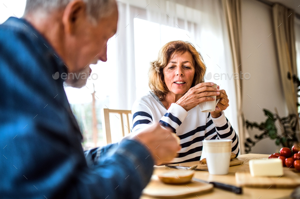 Senior couple eating breakfast at home. Stock Photo by halfpoint | PhotoDune
