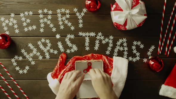 Santa Claus Plays with Fidget Spinner and Puts It in Gift Box on Christmas Table, Top Down Shot