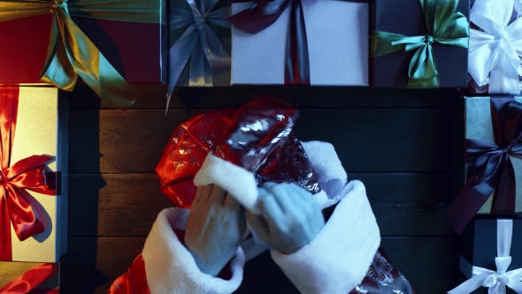 Man in Santa Claus Suit Puts on His Gloves By Wooden Decorated New Year Table, Top Down Shot