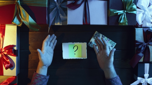 Adult Man Opens New Year Present Box with Sticky Note with Question Mark on It, Top Down Shot