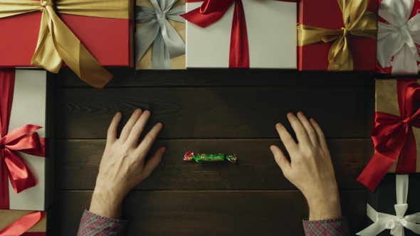 Adult Man Unwraps Candy, Eats It and Throws Wrapper on Christmas Decorated Desk, Top Down Shot