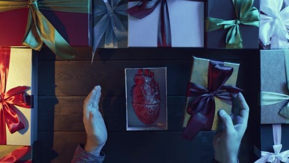 Adult Man Opens New Year Gift Box with Anatomical Human Heart Made of Plastic Inside on Decorated